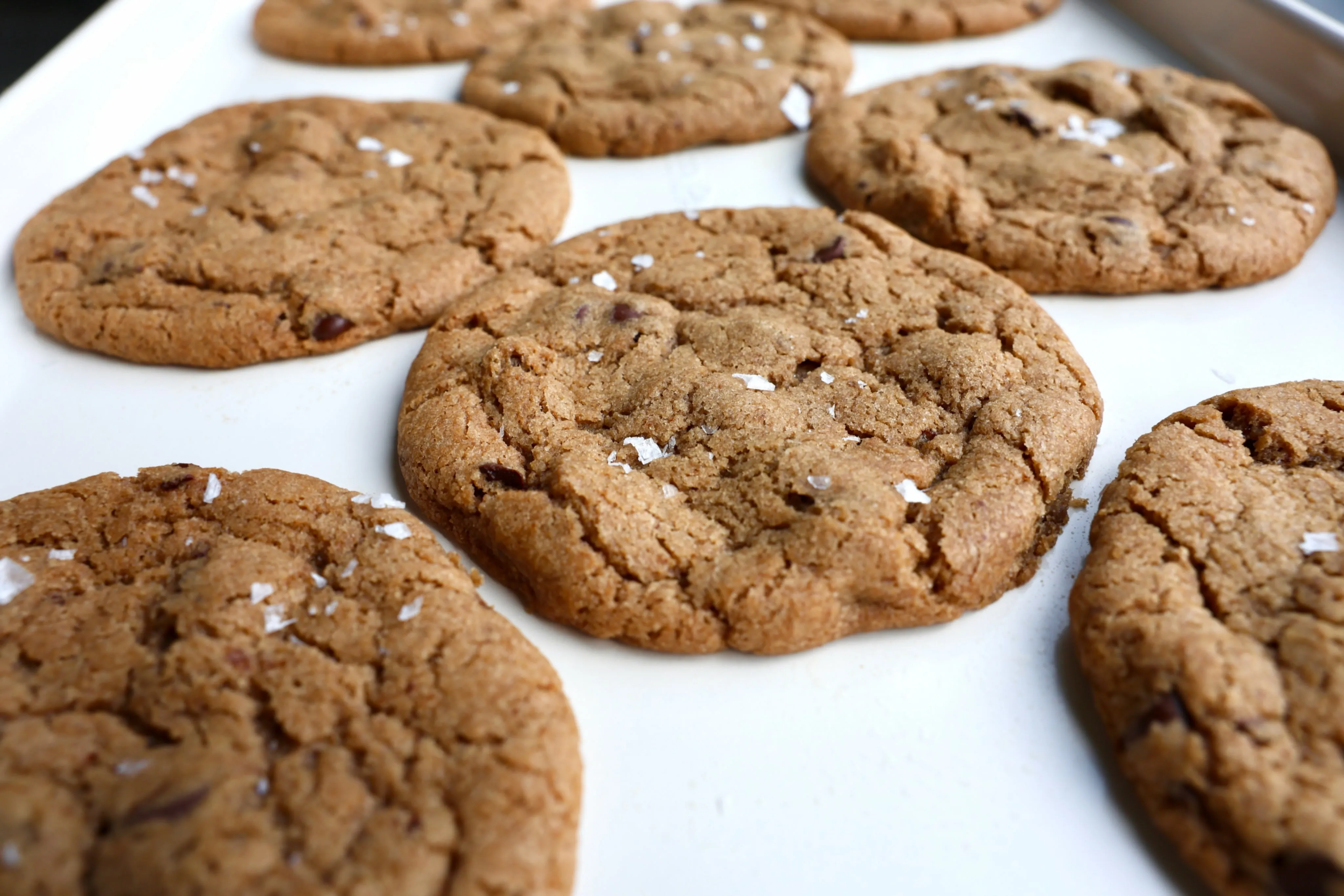 Espresso chocolate chip cookies topped with flaky salt on a baking sheet